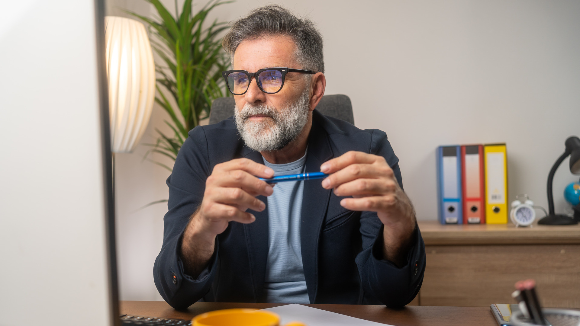 Mann med skjegg og briller ser inn i PCen, antagelig på et hjemmekontot